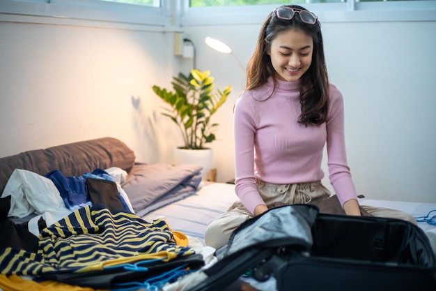 Femme emballant des vêtements dans des bagages à la maison se préparant à voyager