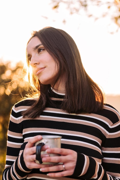 Une femme embrasse le plein air et trouve la paix avec du thé