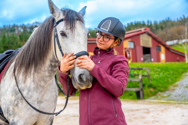 Une femme embrasse son cheval devant un ranch.