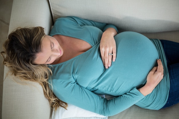 Femme enceinte à l&#39;aide d&#39;une tablette allongée sur le canapé dans le salon