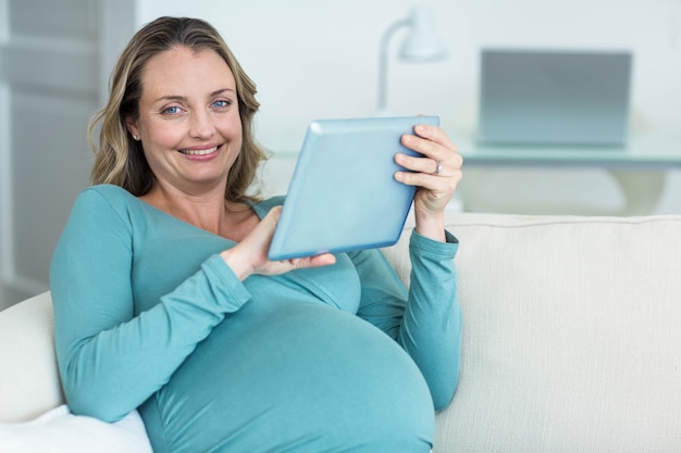 Femme enceinte à l&#39;aide d&#39;une tablette PC sur le canapé