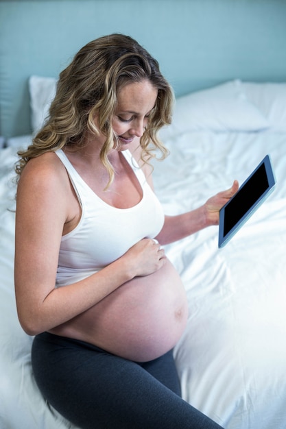 Femme enceinte à l&#39;aide d&#39;une tablette PC sur son lit