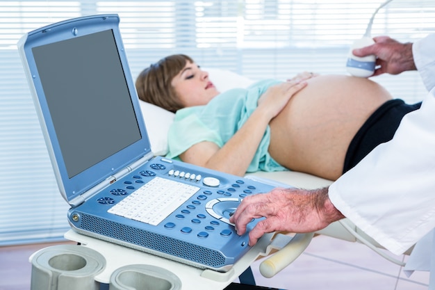 Photo femme enceinte allongée pendant que le médecin effectue un test échographique