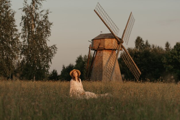 Photo une femme enceinte à l'arrière-plan du moulin se détend sur l'herbe et se tient le ventre