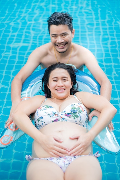 Femme enceinte asiatique. Maman et nouveau-né. Fête des mères et journée internationale de la femme. Détendez-vous et récréez avec votre mari à la piscine.