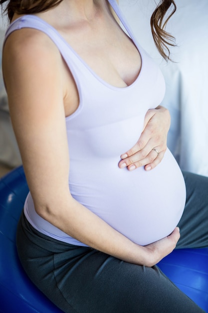 Femme enceinte assise sur un ballon d&#39;exercice à la maison