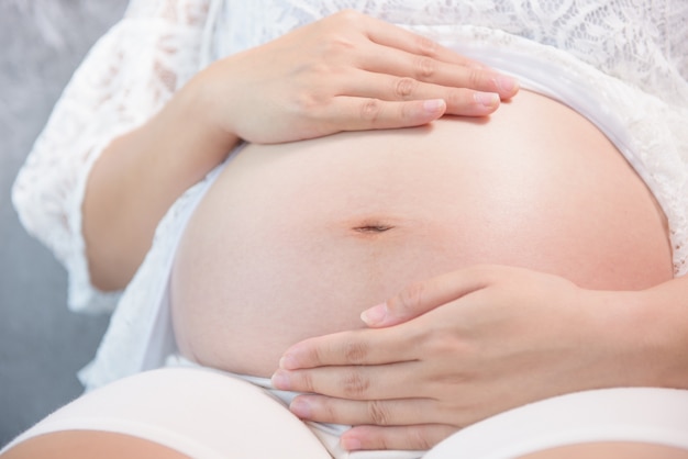 femme enceinte assise sur le canapé se bouchent