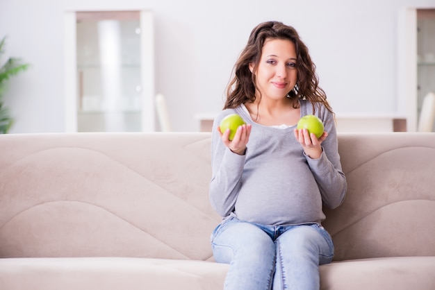 Femme enceinte assise sur un canapé