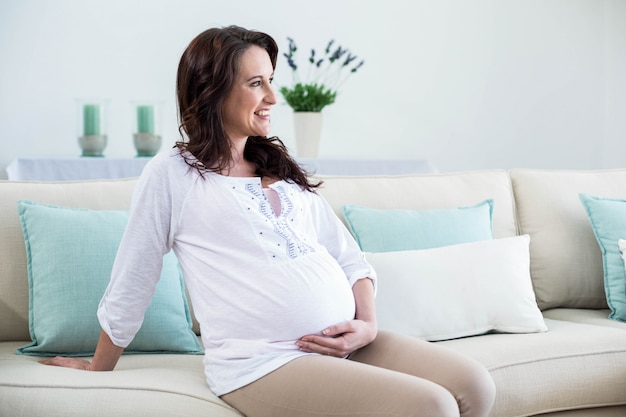 Femme enceinte assise dans le salon à la maison