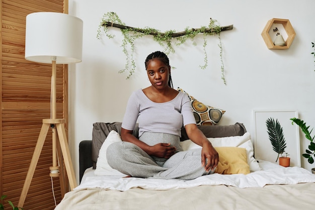 Femme enceinte assise sur le lit