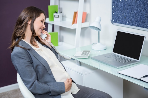 Femme enceinte au téléphone au bureau à domicile