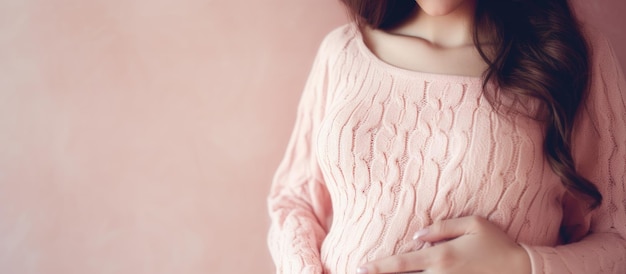 Femme enceinte au ventre rond portant un pull rose