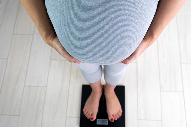 Photo une femme enceinte sur une balance contrôle son gain de poids grossesse en bonne santé