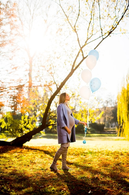 Femme enceinte avec des ballons dans le parc en automne