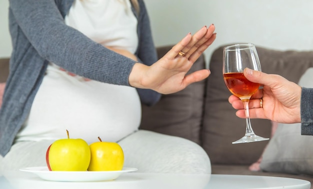 Une femme enceinte boit du vin dans un verre Mise au point sélective