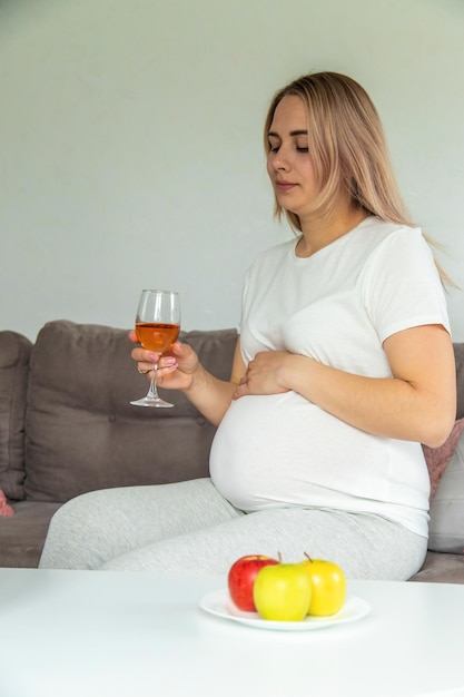Une femme enceinte boit du vin dans un verre Mise au point sélective