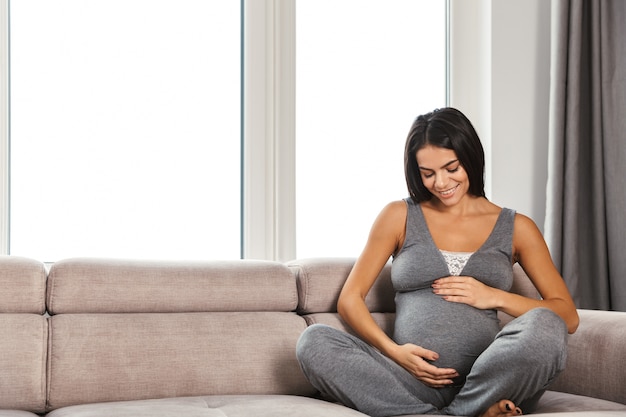 Femme enceinte en bonne santé à l'intérieur à la maison assis posant.