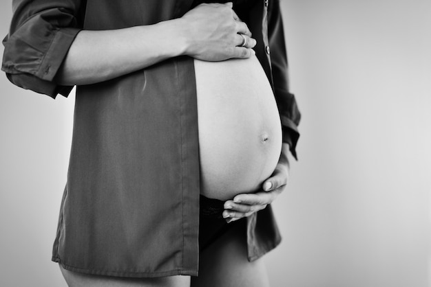 Une femme enceinte en bonne santé utilise sa main pour tenir le bébé dans l'utérus avec un éclairage sombre