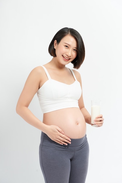 Femme enceinte buvant du lait sur fond blanc.