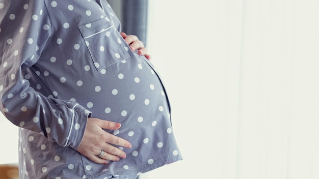 La femme enceinte caresse le ventre et attend le bébé à venir