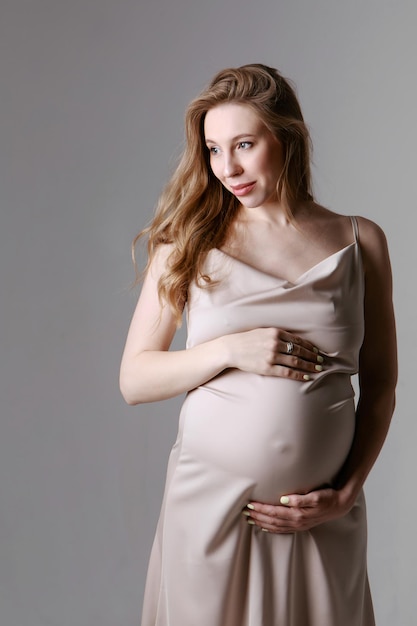 Femme enceinte caucasienne caressant son ventre sur fond blanc. Espace de copie. Le concept de digestion saine, mode de vie, FIV