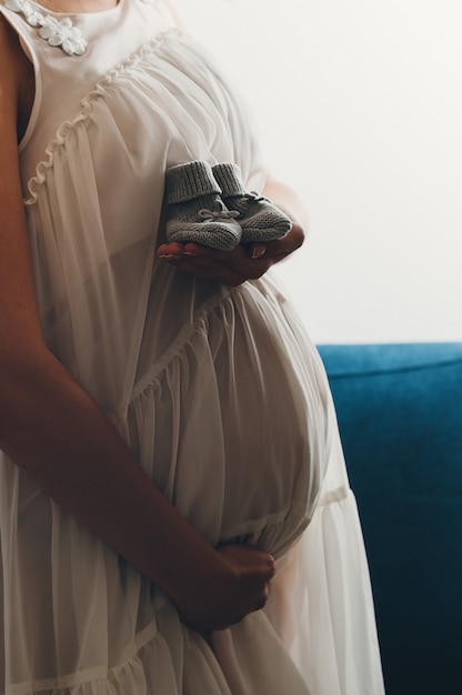 Photo femme enceinte avec des chaussures en tricot de bébé sur sa main