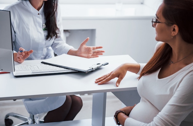 Une femme enceinte consulte un obstétricien à l'intérieur.