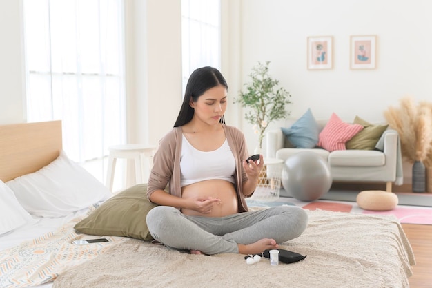 Photo une femme enceinte contrôle le taux de sucre dans le sang à l'aide d'un glucomètre numérique