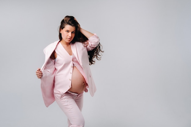 Femme enceinte en costume rose gros plan sur fond gris