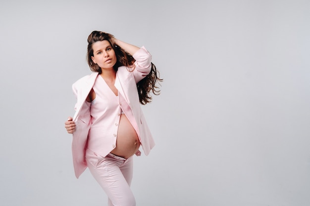 Femme enceinte en costume rose gros plan sur fond gris