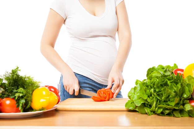 La femme enceinte coupe la tomate à bord en gros plan