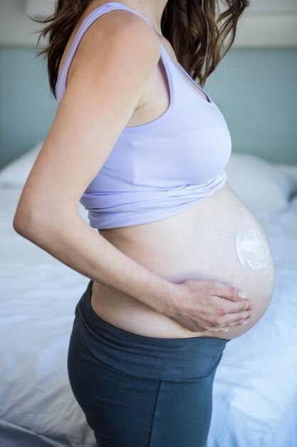 Femme enceinte, à, crème, ventre, chambre à coucher