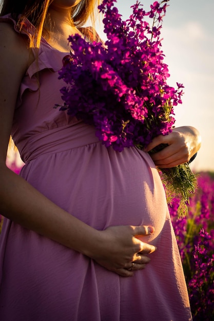 Photo une femme enceinte dans un champ de fleurs violettes