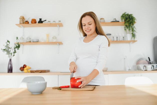 Femme enceinte dans la cuisine faisant de la salade