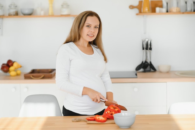 Femme enceinte dans la cuisine faisant de la salade