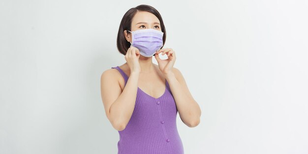 Femme enceinte dans un masque de protection contre la grippe et les virus sur fond blanc