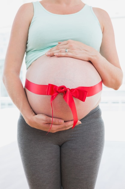 Femme enceinte debout avec un arc rouge autour du ventre