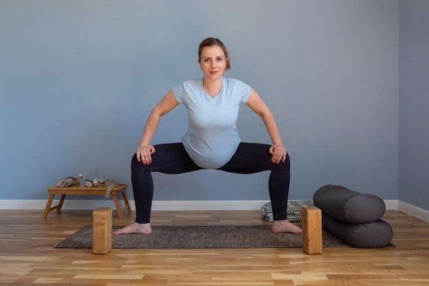 Femme enceinte debout dans l'exercice Sumo Squat, pose de la déesse