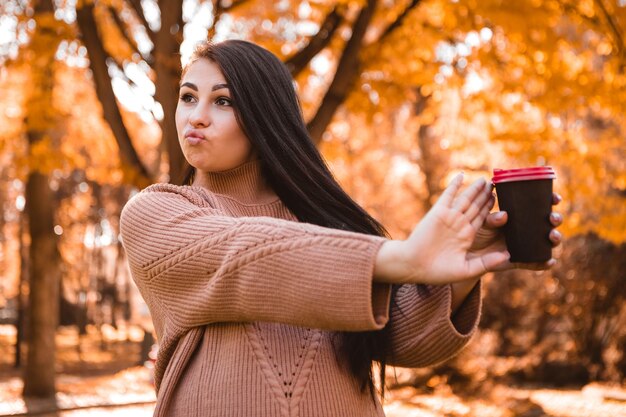 Femme enceinte debout dans la forêt du parc de la ville d'automne, caressant le ventre rond avec un bébé à l'intérieur