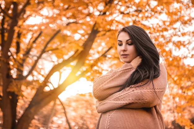 Femme enceinte debout dans la forêt du parc de la ville d'automne, pull en laine chaud habillé
