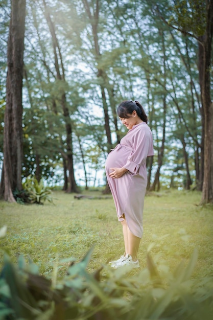 Une femme enceinte debout dans un parc.