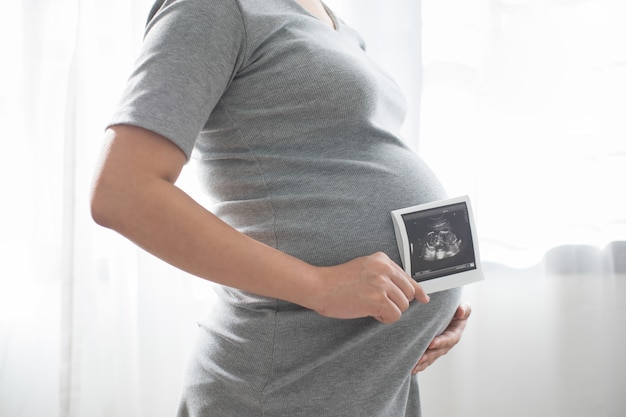 Femme enceinte, debout, fenêtre