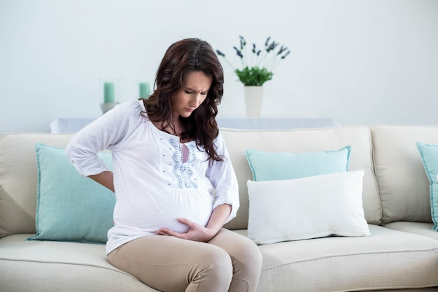 Femme enceinte avec dos douloureux dans le salon