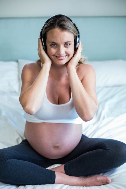 Femme enceinte en écoutant de la musique sur son lit