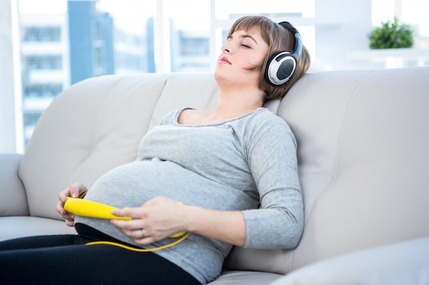 Femme enceinte en écoutant de la musique avec les yeux fermés