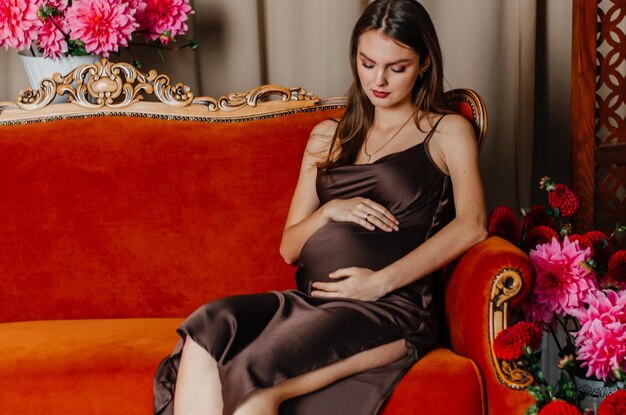 Une femme enceinte est assise sur un canapé rouge