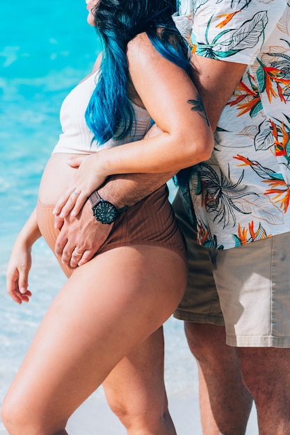 Une femme enceinte est debout sur la plage avec son mari.