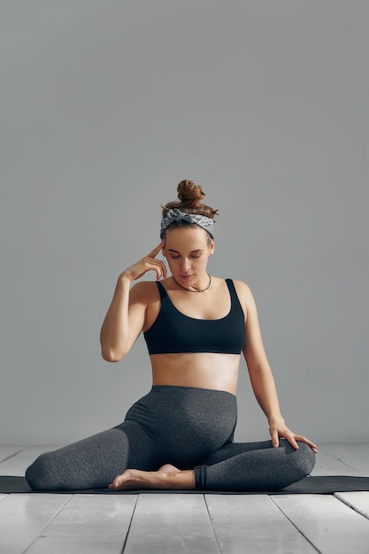 Femme enceinte étirant les bras et les jambes faisant de l'entraînement prénatal à la maison sur un tapis de yoga mise au point sélective