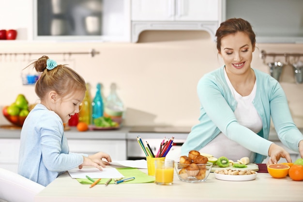 Femme enceinte faisant le dîner tandis que sa fille peignant