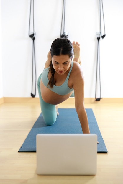 Femme enceinte faisant du yoga en ligne avec son ordinateur portable